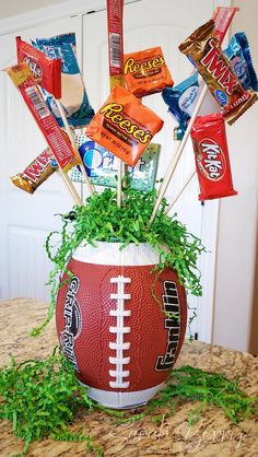 a football planter filled with candy bars and candies on top of a table