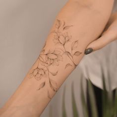 a woman's arm with a flower tattoo on the left side of her arm