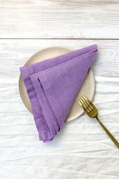 a purple napkin and fork on a white plate