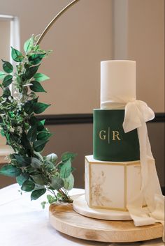 a wedding cake sitting on top of a table next to a vase with greenery