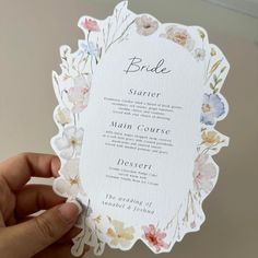 a person holding up a wedding card with flowers on the front and back of it