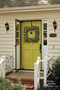 a yellow front door with a wreath on it