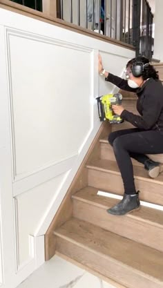 a woman is sitting on the stairs with a drill and some glue in her hand