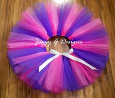 a purple and pink tulle skirt with a white bow on the bottom that says happy g designs