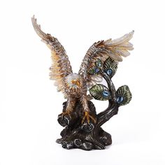 a statue of two birds sitting on top of a tree branch with wings spread out