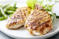 two pieces of chicken on a plate with green beans