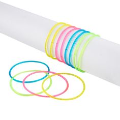 a stack of colorful bracelets sitting on top of a white paper tube next to each other