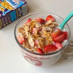 a bowl of cereal with strawberries and yogurt in it next to a box of cereal