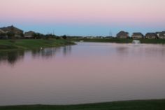 a lake with houses in the background at dusk