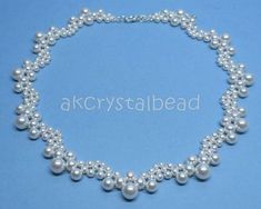 a necklace with white pearls and crystal beads on a blue background, the bead is attached to a silver chain