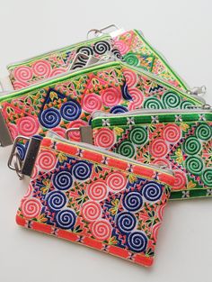 four zippered purses with colorful designs on them are sitting next to each other