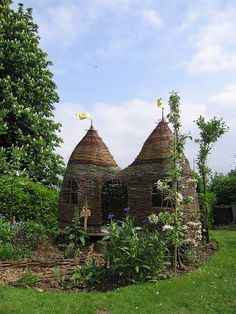 an old house made out of bricks and straw in the middle of a garden area