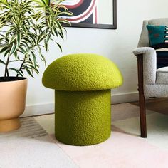 a green stool sitting in front of a potted plant next to a gray chair