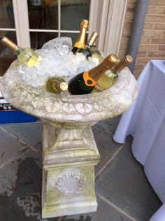 a fountain with bottles of wine in it and ice on the ground next to a table