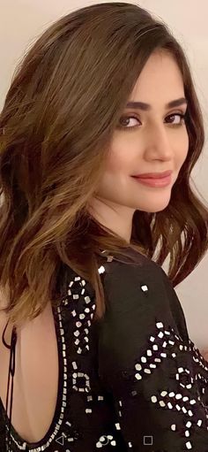 a woman with long brown hair wearing a black and white top smiling at the camera