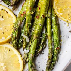 asparagus spears with lemon slices and parmesan sprinkles on a white plate