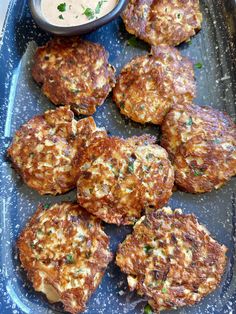 several crab cakes on a blue plate with dipping sauce