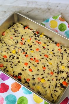 a cookie dough in a metal pan on a polka dot tablecloth with colorful dots