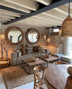 a living room filled with furniture next to a wooden table and two round mirrors on the wall