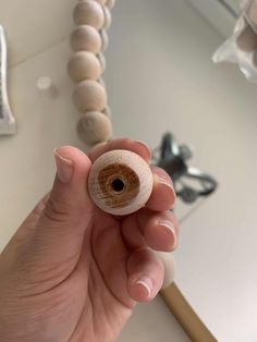 a person holding a wooden bead in their hand near a bathroom sink and mirror