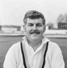 black and white photograph of a man wearing a cricket uniform with a moustache on his face