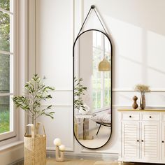 a mirror sitting on top of a wooden floor next to a vase and potted plant