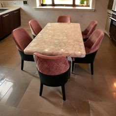 a dining room table with pink chairs in front of it and an oven on the other side