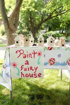 a sign that says paint a fairy house on it in front of some trees and grass