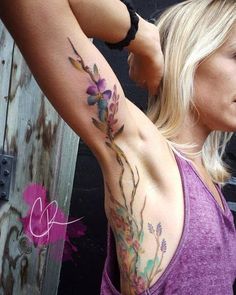 a woman with a tattoo on her arm and behind her is a purple tank top