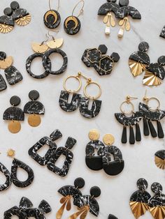 black and gold earrings are laying on a white table top, with one earring in the middle