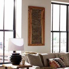 a living room filled with furniture and large windows next to a wall mounted brick fireplace