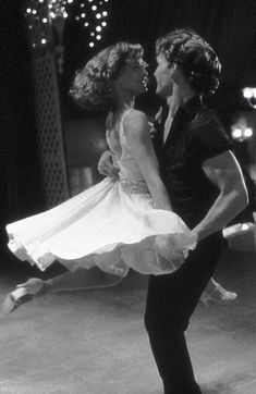 a man and woman dancing on stage in the middle of a dance floor with lights behind them