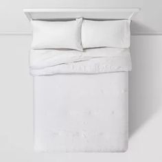 a white bed with two pillows on top of it