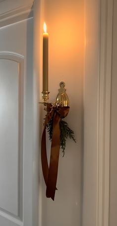 a candle is lit on the wall next to a door with a ribbon around it