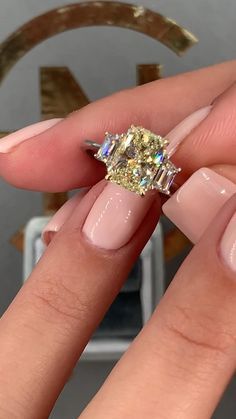 a woman's hand with a ring on it and a yellow diamond in the middle