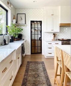 a kitchen with white cabinets and an area rug in front of the counter top that matches the floor