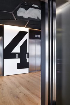 an elevator with the number four painted on it's wall and wooden flooring