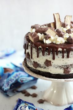 a cake with chocolate and marshmallows on it sitting on a white pedestal