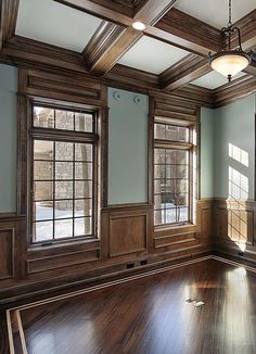 an empty room with wood paneling and windows