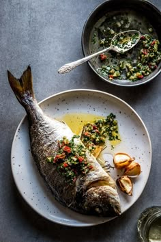 a fish is on a plate with some vegetables and sauces next to the dish