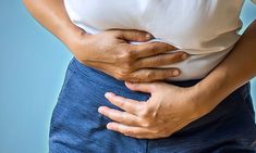 a woman holding her stomach with both hands and showing it's lower back area