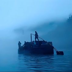 a man standing on the end of a boat in the middle of foggy water