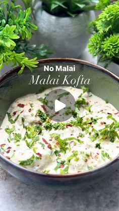 a bowl filled with white sauce and garnished with herbs