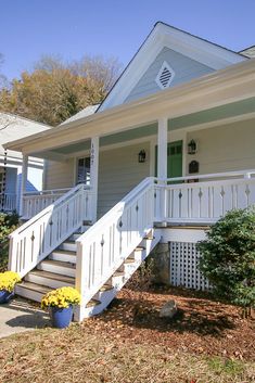 a white house with steps leading up to the front door and second story porch area