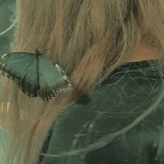 a butterfly sitting on the back of a woman's head with long blonde hair