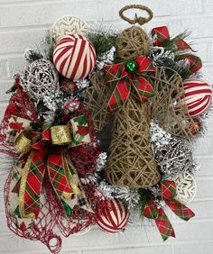 a christmas wreath with ornaments hanging on the side of a brick wall next to a white brick wall