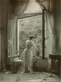 an old black and white photo of a woman in front of a window