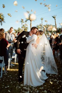 a bride and groom kiss as they walk down the aisle at their wedding ceremony in palm trees