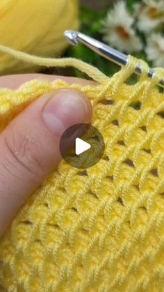 someone is knitting the stitchs on a yellow piece of yarn