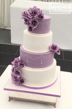 a three tiered cake with purple flowers on top